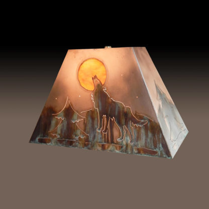 Western Style Copper Lamp Shade of Wolf Howling at the Moon under starry night. Evergreen with mountain in background. Sides of shade have ever green design.
